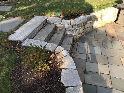 Cut antique granite with a fieldstone retaining wall and bluestone patio