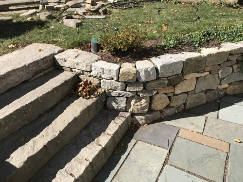 Cut antique granite with a fieldstone retaining wall and bluestone patio